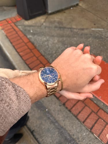Customer wearing the rose-gold Lucky Fours® Ronin watch with a blue dial while holding another person's hand.