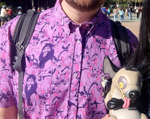 Customer wearing the purple "Long Live the King" shirt featuring a Scar and hyena pattern at a theme park.