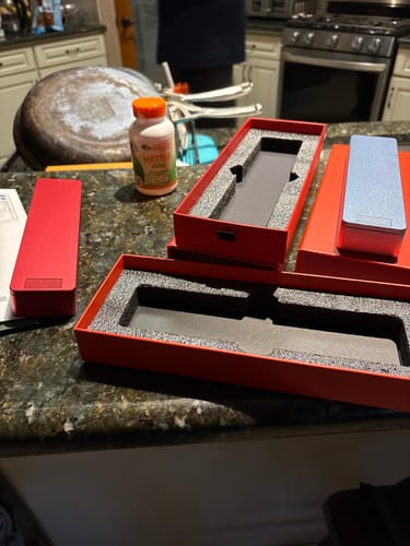 Customer's new 2-Pack Bundle of metal pill cases, showing the red and silver cases and their boxes on a kitchen counter.