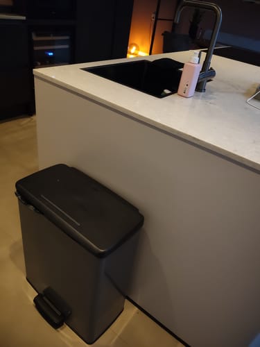 Recensent toont de grijze Curver Decobin Duo prullenbak die naast een modern keukeneiland staat.
