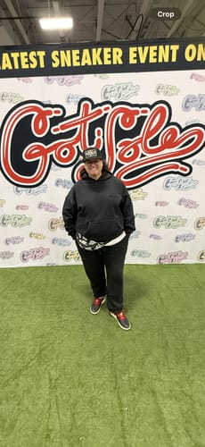 Reviewer wearing the Massachusetts Blackout Plate Hat while standing in front of a banner for a sneaker event.