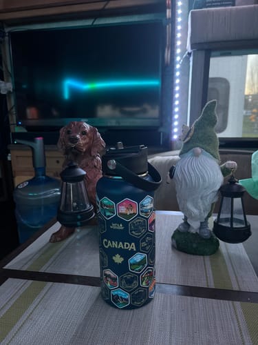 Customer's Canada Bottle on an indoor table, decorated with many stickers from their Canadian travels.