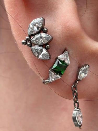 Customer's ear showing the MarquiseDrop Titanium Flat Back Stud with a dangling gem, worn alongside other earrings.