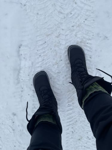 Asiakkaan mustat Vaistoa Hanki 2 -talvisaappaat jalassa lumisessa maastossa.