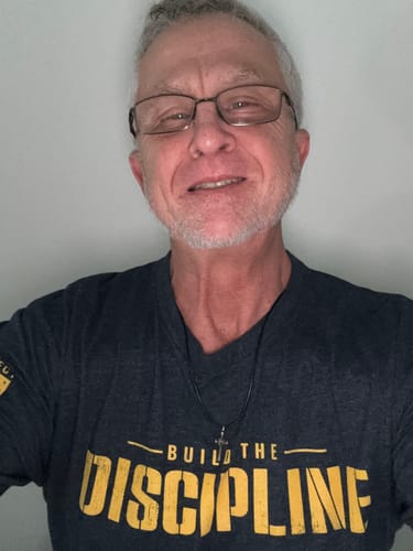 Customer wearing the dark grey 'Do the Work' tee, showing the yellow 'Build The Discipline' graphic.