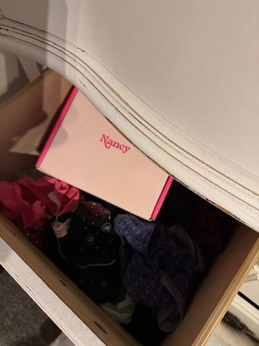 Reviewer's image of a box containing their Lem Clitoral Massager nestled amongst clothes in a dresser drawer.