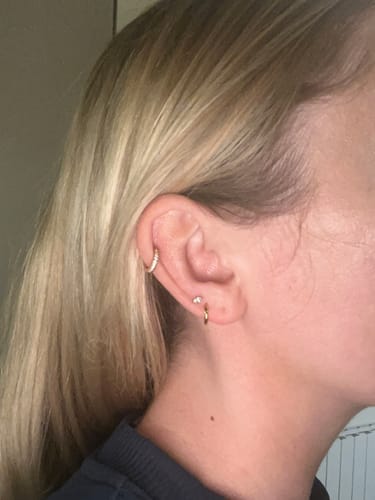 Customer wearing the gold Faux Hoop Crystal Flatback earring in their helix piercing, alongside other small earrings.