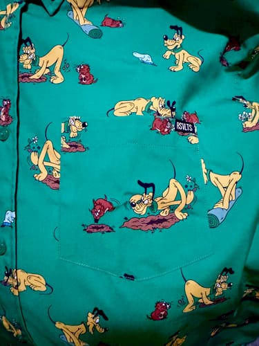 Close-up of the reviewer's green shirt showing the detailed 'Pluto and the Gopher' pattern.