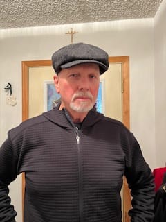 A customer wearing the dark JP Cap Tweed in a herringbone pattern indoors.