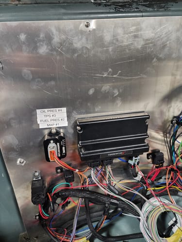 Reviewer's black RIFE 5V Plus+ Wiring Module installed on a metal panel amidst complex wiring for a new build.