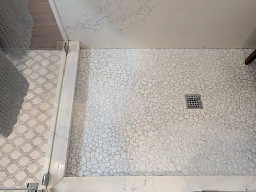 Reviewer's view of a pebble-stone shower floor before using the Bathroom Concentrate.