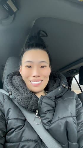 Reviewer in a car smiles, showing off their bright and natural-looking Spare Veneers.