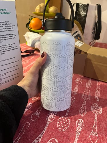 Customer holding their white World Explorer Bottle, showing the detailed destination engravings.