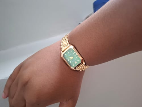 Customer's CLAIRE DE MAINS watch on their wrist, showing the gold band and green face.