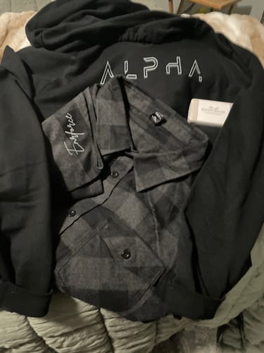 Customer's Lifestyle Bundle hoodie shown with a plaid shirt and soap bar laid out on a bed.