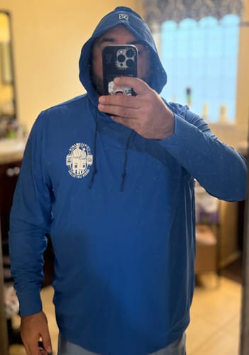 Reviewer wearing the blue 'Ichiraku Ramen' Performance Hoodie with the hood pulled up in a mirror selfie.