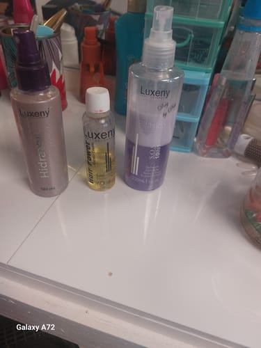 El Spray Bifásico 10 en 1 de un cliente sobre un tocador blanco junto a otros productos para el cabello.