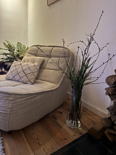 De beige bouclé fauteuil van een klant in een hoek van de kamer, naast een houten vloer.