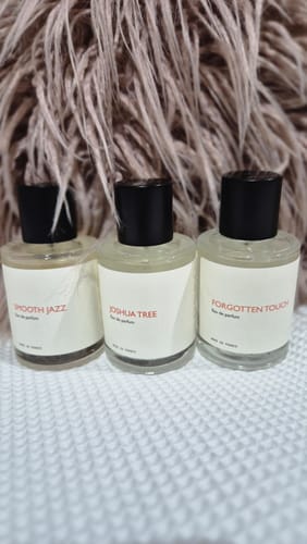 Customer's three perfume bottles, including their favorite Smooth Jazz, set on a white textured surface.