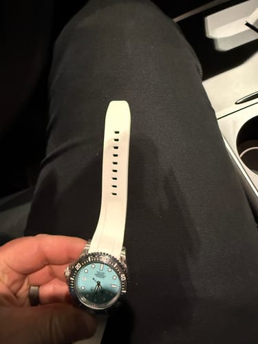 Reviewer holding the Oceaneva watch with a sky blue dial, showing the full length of the white rubber strap.