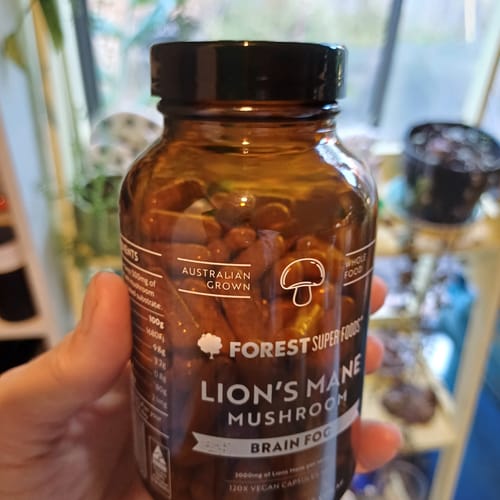 Reviewer holding an amber bottle of Australian Grown Lion's Mane Mushroom Capsules.