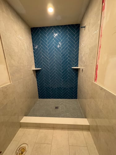 Customer's image of a shower stall with a blue herringbone tile wall; the product is not shown.