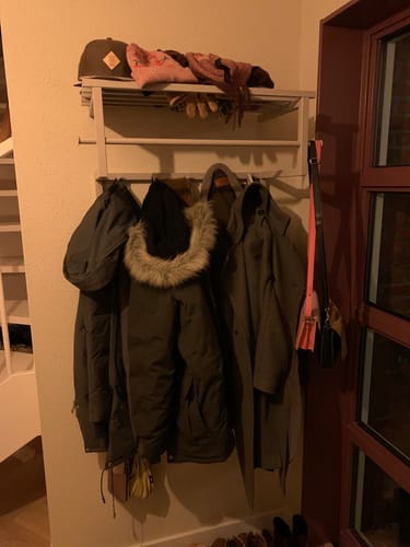 De Rizzoli wandkapstok van een klant, gemonteerd in een hal en beladen met jassen en accessoires.