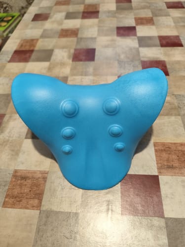 Vásárló kék Kiropraktikus Nyak- és Váll Lazító Párnája egy kockás asztalon.