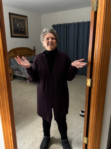 Reviewer wearing a cozy outfit, featuring the black Peyton Turtleneck layered under a long cardigan.