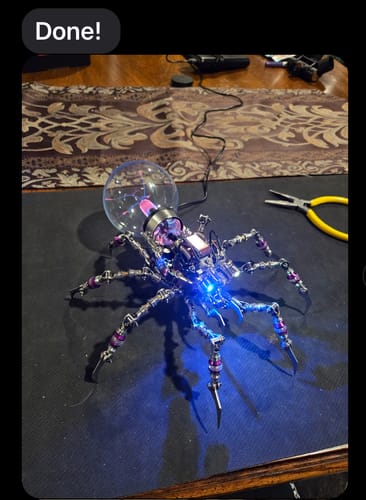 Customer's assembled Cyberpunk Plasma Ball Spider glowing with a blue LED and plasma ball on a desk.