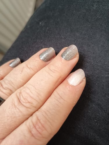 Kundenfoto einer Hand mit kurzen Nägeln, die glitzernde Nagelfolien in Silber und Hellrosa tragen.