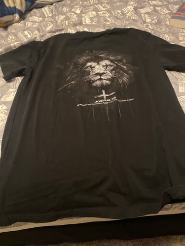 Reviewer's black t-shirt with a lion and cross graphic laid out on a patterned bedspread.