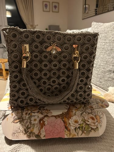 Customer's completed grey Garden Bee Crochet Bag with gold hardware and a bee detail, shown from the front.