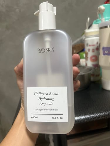 Customer holding the large 400ml bottle of Bad Skin Collagen Bomb Hydrating Ampoule.