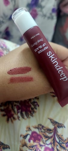 Customer holding the Peptide Lip Glaze in Deep Berry with two color swatches on the back of their hand.
