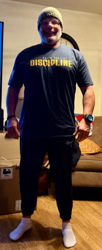 Reviewer standing in a room wearing the dark blue Do the Work tee, showing its athletic fit.