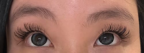 Close-up on a reviewer's eyes wearing the Dewdrop Grayish Blue contacts over their natural dark brown eyes.