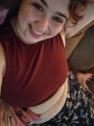 Customer smiling while wearing the gold Crystal Tie On Waist Beads around her waist with a red top.