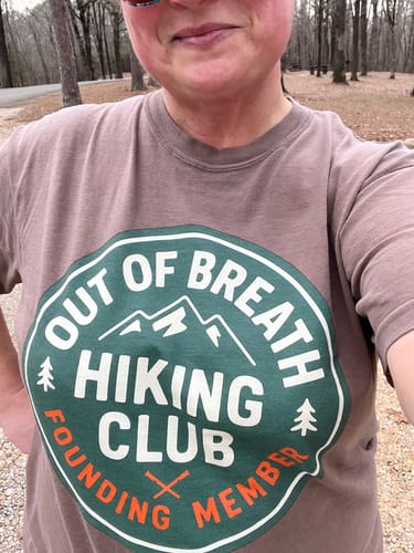 A close-up of a reviewer wearing the brown Founding Member T-Shirt outdoors.