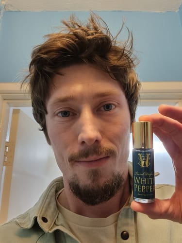 Reviewer holding a travel-size bottle of the White Pepper fragrance.