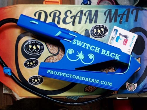 Customer's new blue Switchback Clean-Up Sluice Box displayed with its hose, stickers, and manual on a colorful mat.