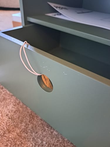 Klant toont afbladderende verf op de lade van het groene WOOOD Ozzy Nachtkastje.