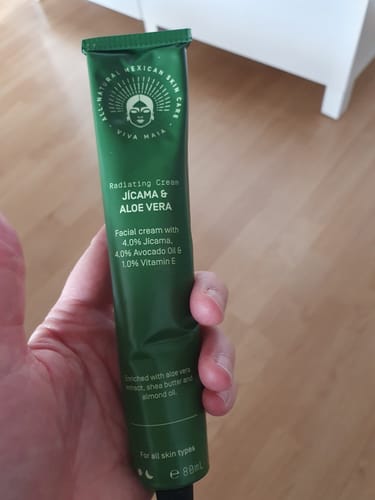 Reviewer holding the green aluminum tube of Radiating Cream.