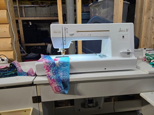 Customer's Baby Lock Jazz 2 sewing machine on a table, showing the large throat space while sewing colorful fabric.
