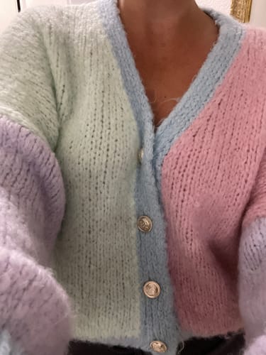 Kunde trägt den pastellfarbenen, weichen Oversized Cardigan mit bronzefarbenen Knöpfen in Nahaufnahme.