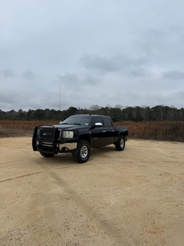 Customer's black GMC Sierra truck with wheel spacers installed, parked on a dirt road.