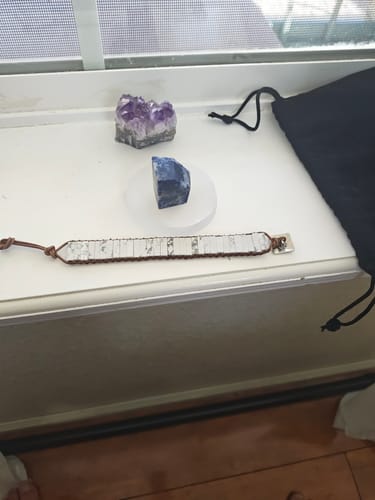 Customer's beautiful AuraBloom Box items: a white beaded bracelet, an amethyst cluster, and a blue crystal on a windowsill.