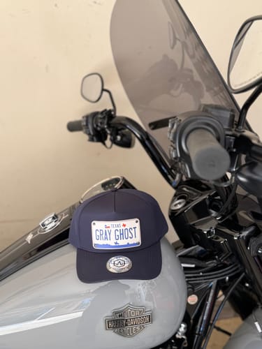 Customer's Texas 2000 Plate Hat with 'GRAY GHOST' customization, resting on the gas tank of a motorcycle.