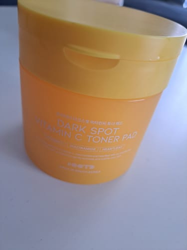 Клиент показва оранжево-жълтата опаковка на тонер падовете OOTD Dark Spot Vitamin C.