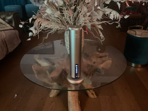 Customer's silver LumaMax diffuser lit up on a glass coffee table in a modern living room.